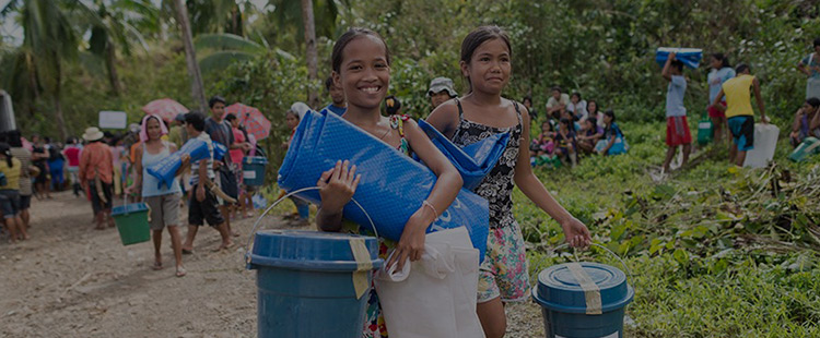Photo of smiling women carrying bags of food and water
